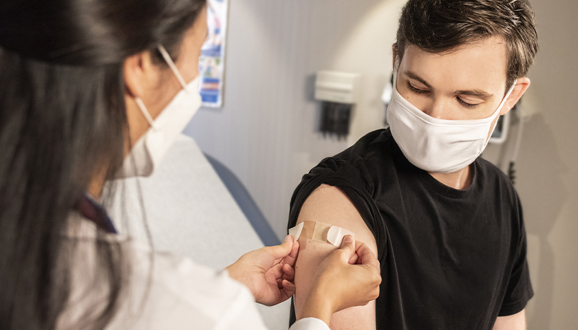 In this 2020 photograph, captured inside a clinical setting, a health care provider places a bandage on the injection site of a patient, who just received an influenza vaccine. The best way to prevent seasonal flu, is to get vaccinated every year. Centers for Disease Control and Prevention (CDC) recommends everyone 6-months of age and older get a flu vaccine every season.
