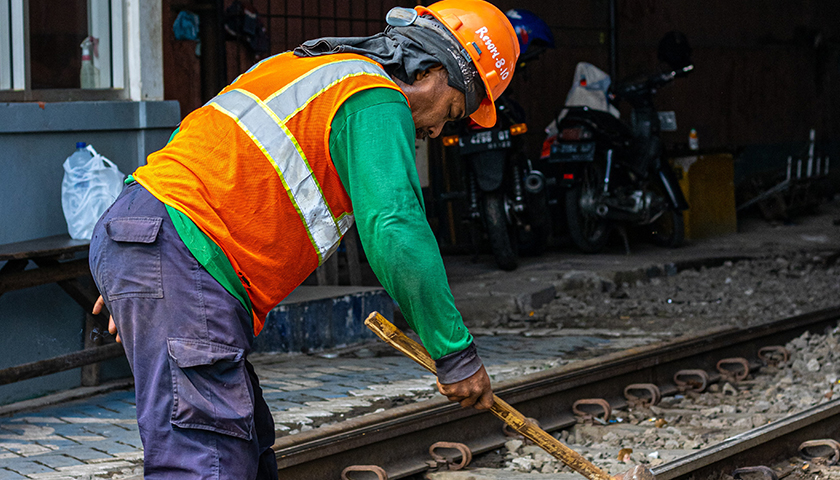 Worker using a sledgehammer on railroad