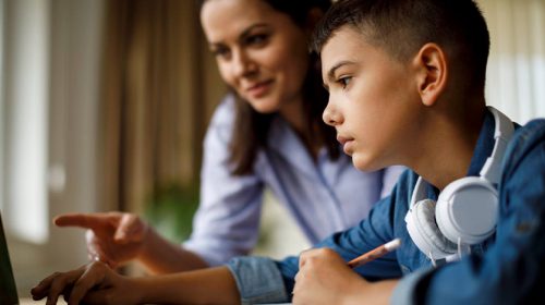 Child learning online with mother next to boy