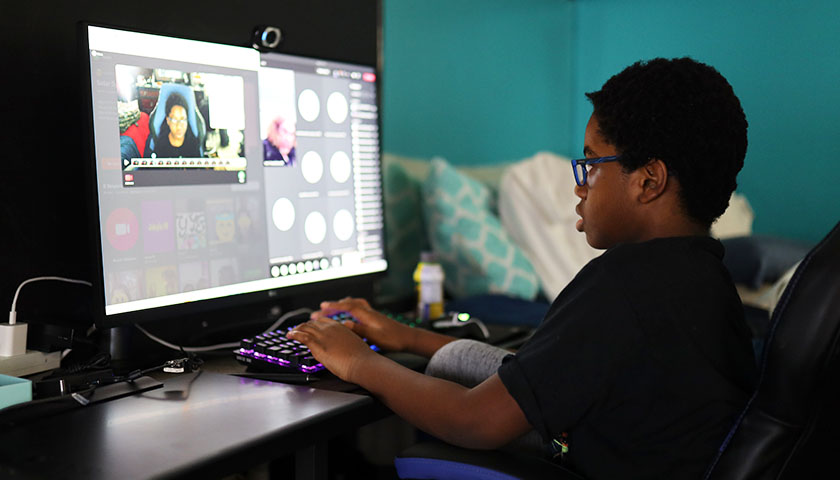 Young boy on desktop computer doing virtual learning with video chat