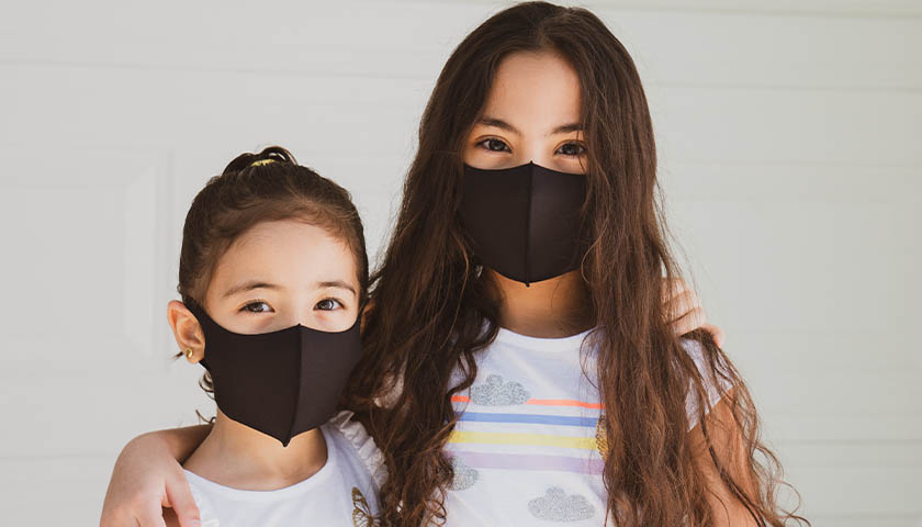 Two young, brunette girls wearing black masks