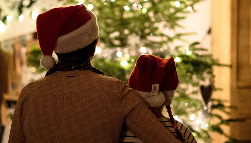 two people with Santa hats looking at Christmas tree