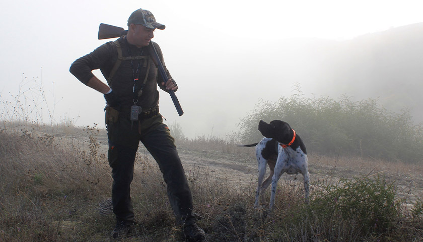 man in hunting gear with dog